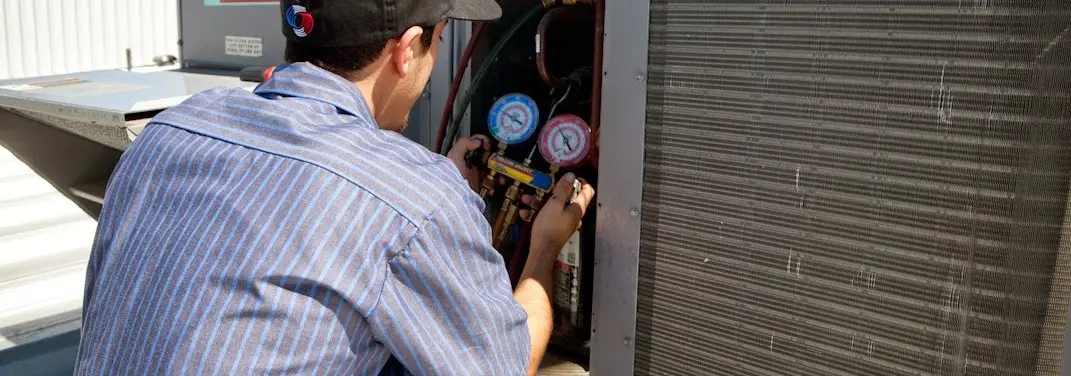HVAC technician servicing a condenser unit in Louisburg