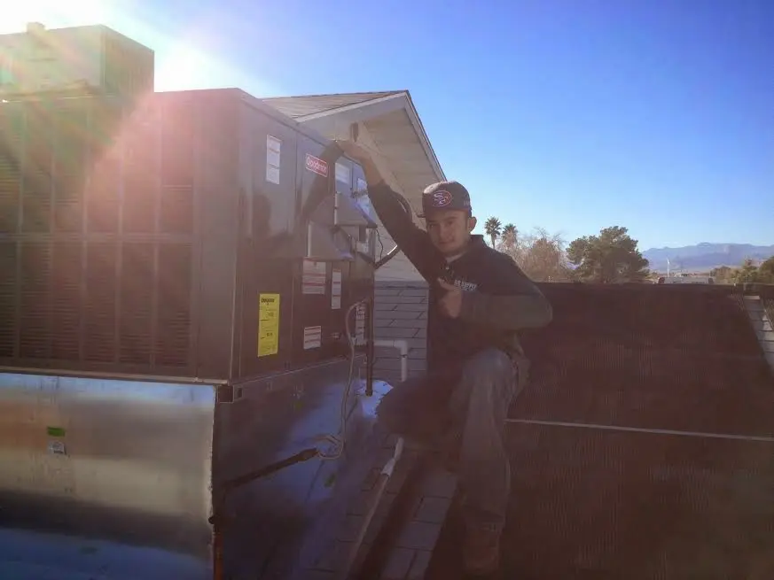 HVAC technician performing Air Duct Repair on a rooftop unit in Louisburg